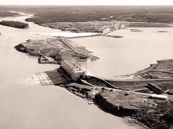 The completed Kelsey Generating Station with its powerhouse in the foreground and spillway in the background.