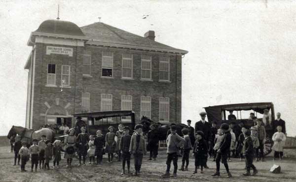 Students and a pair of transport vans in front of Darlingford Consolidated School