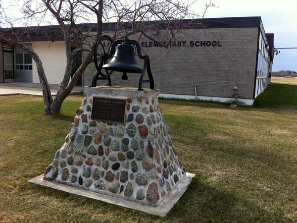 Monument for the Langruth School, topped by its bell, in front of the present elementary school at N50.38300, W98.67489