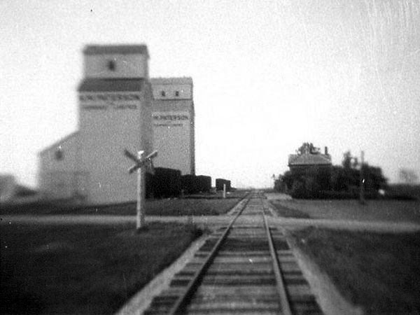A railway station at right stood opposite two grain elevators, older in foreground and younger in background, at Ridgeville