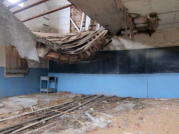 Interior of St. Raymond School building, with collapsing floor of the teacherage on the second floor