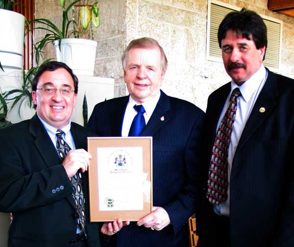 Manitoba Lieutenant-Governor, The Honourable John Harvard (center), presents a MHS Centennial Organization Award
to AMM Executive Director Joe Masi (left) and AMM Vice President Garry Wasylowski (right) at a ceremony on 23 April 2006.