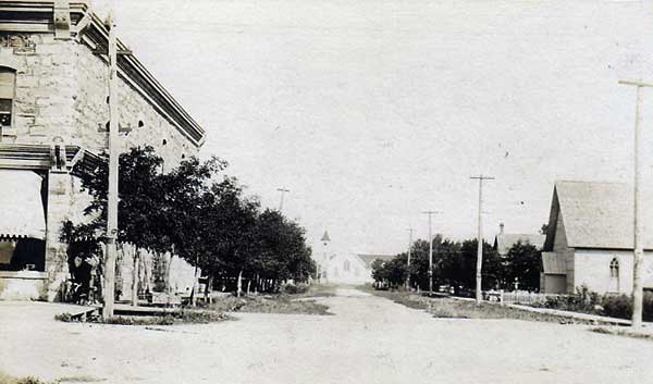 Postcard view of Eighth Street in Morden with the Land Titles Office at left and St. Thomas Anglican Church at right