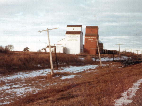 Red-coloured Pioneer grain elevator at Glossop, with a white Manitoba Pool grain elevator beside it