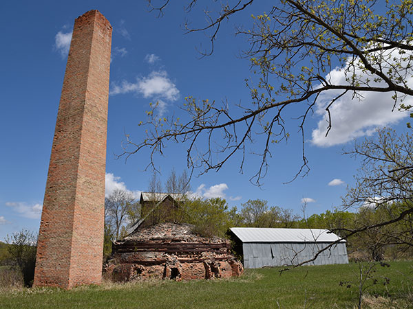 The former Leary Brickworks showing, from left to right, the kiln chimney, beehive kiln, brick press building, and drying shed at right