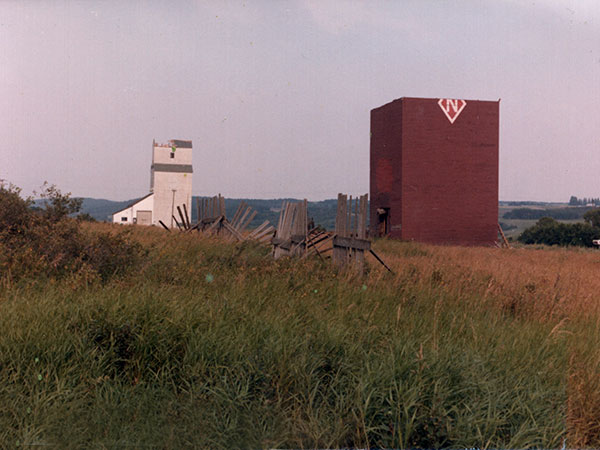 Manitoba Pool grain elevator undergoing demolition in background of National grain elevator