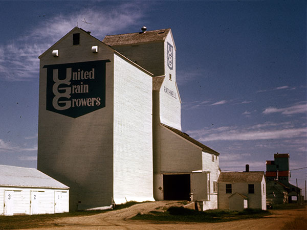 The United Grain Growers grain elevator with its crib annex at Rathwell, with Paterson at right