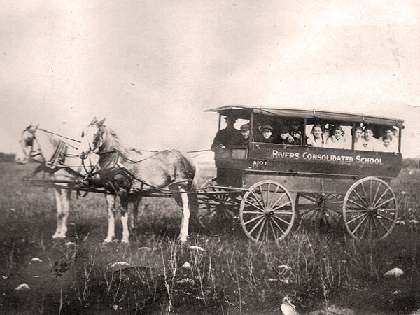 Van used to transport students to the Rivers Consolidated School, with driver Bob Mills. Male students were unidentified but girls were (left to right): Violet Bowman, Fanny Varcoe, Belle Robins, Eva Robins, Peg Robins, and Mabel Bowman